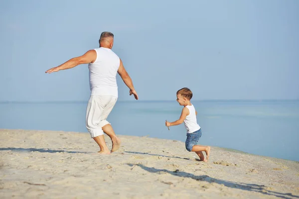 Vater spielt mit seinem kleinen Sohn am Strand — Stockfoto