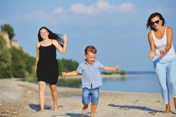 Eine fröhliche Familie läuft im Sommer am Strand entlang — Stockfoto