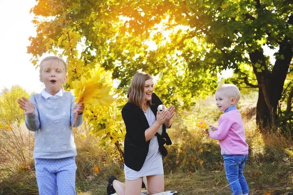 Молода мама розважається з дітьми на пікніку в осінньому парку — стокове фото