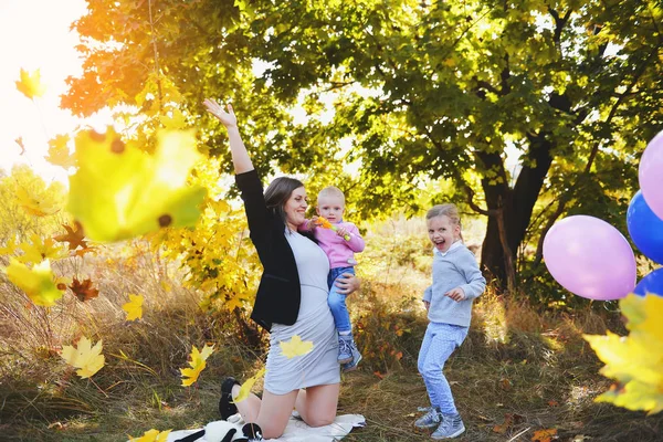 Молода мама розважається з дітьми на пікніку в осінньому парку — стокове фото