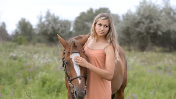 Een jonge vrouw staat in de buurt van een paard en lijnen van het. — Stockvideo