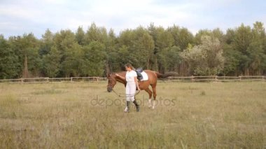 Bir genç kadın jokey alanın karşısındaki onun atı sürücüler.