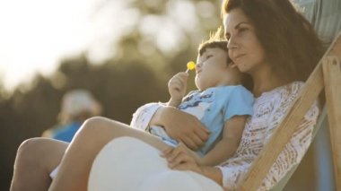 Anne oğluyla bir koltuk sahilde yaz gün batımında oturuyor.