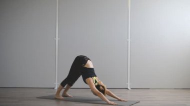 Genç bir kadın sonbahar sabahı parkta yoga yapıyor..