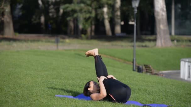 Eine junge Frau praktiziert am Herbstmorgen Yoga in einem Park. — Stockvideo