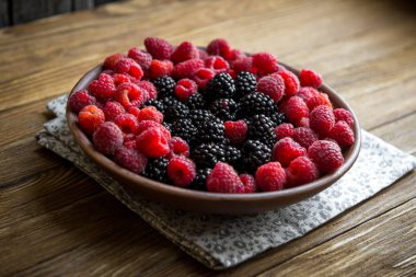 taze Ahududu ve böğürtlen ahşap bir masa üzerinde bir seramik kase