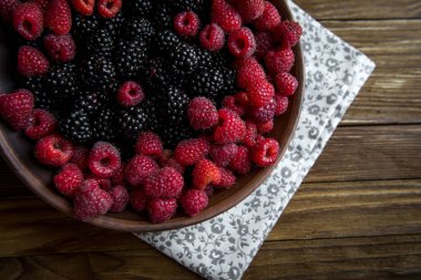 taze Ahududu ve böğürtlen ahşap bir masa üzerinde bir seramik kase
