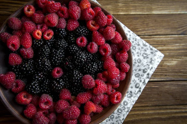 taze Ahududu ve böğürtlen ahşap bir masa üzerinde bir seramik kase