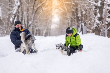 Baba ve oğul kışın köpeklerle parkta yürüyorlar..