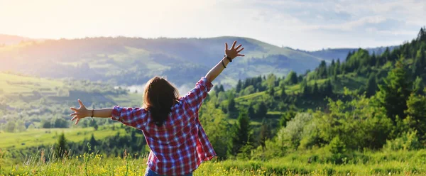 Kız ellerini ve yaz aylarında dağların bir çayır üzerinde duruyor kaldırdı