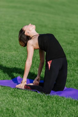 Kız parkta çimlerde yoga yapan.