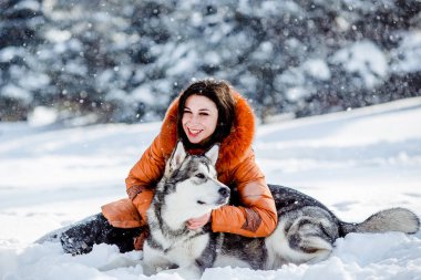 Parkta bir köpek ile kışın oynayan kız.