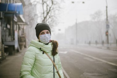 Kız koruyucu tıbbi maskeli karayoluyla duruyor.