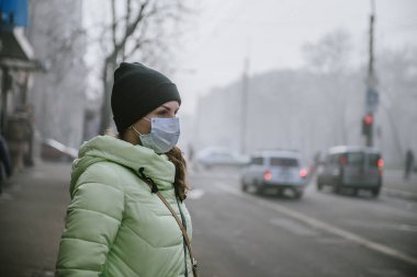 Kız koruyucu tıbbi maskeli karayoluyla duruyor.
