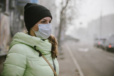 Kız koruyucu tıbbi maskeli karayoluyla duruyor.