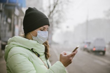 Şehrin koruyucu tıbbi maskeli bir road yakınındaki kadın durumda. Şehrin virüslerden korunma.