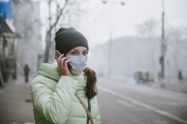 Şehrin koruyucu tıbbi maskeli bir road yakınındaki kadın durumda. Şehrin virüslerden korunma.