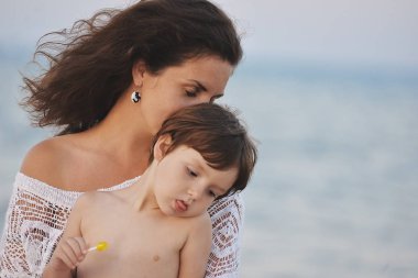 Bir kadın bir çocuk ile yaz aylarında akşam sahilde oturuyor.