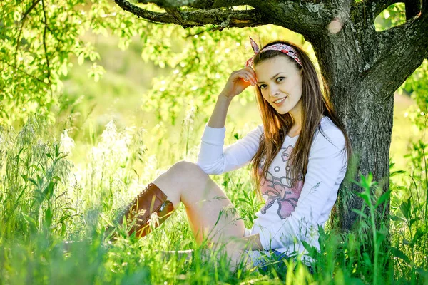 Bella ragazza è seduta sull'erba in giardino — Foto Stock