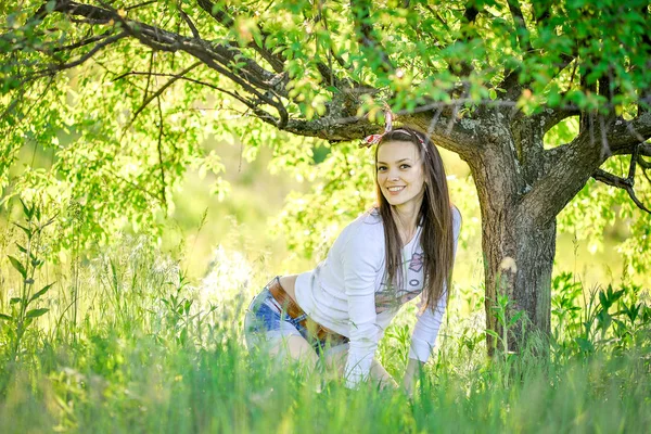 美しい少女は庭の芝生に座っています。 — ストック写真