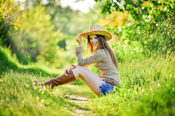 Bela jovem está sentado na grama no jardim — Fotografia de Stock