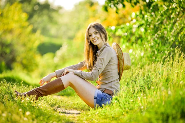 Красива молода дівчина сидить на траві в саду — стокове фото