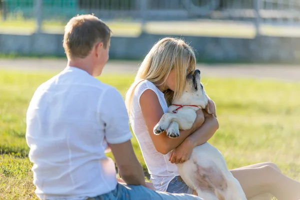 Kvinna med en man som leker med en labrador valp i en park på gräset under våren. — Stockfoto