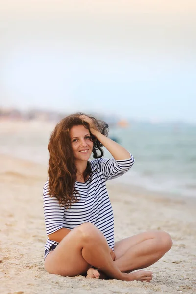 Jovem mulher sentada na praia no verão — Fotografia de Stock