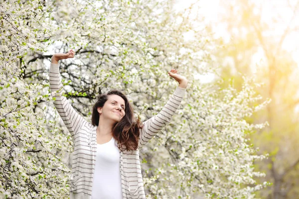 Jeune femme se tient près d'un arbre en fleurs dans un parc de printemps . — Photo