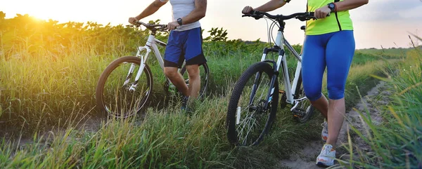 Joven hombre y mujer están conduciendo sus bicicletas en su camino al campo en el verano . — Foto de Stock