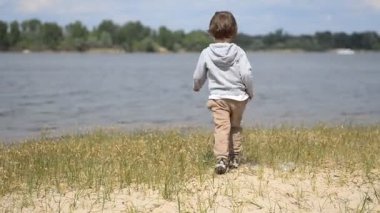 Kum ile baharda kumsalda oynarken yürümeye başlayan çocuk.