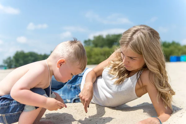 Junge Familie mit Kleinkind ruht sich am Strand aus. — Stockfoto