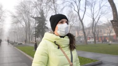 Coronavirus covid-19 'un ikinci dalgası. Sonbaharda şehirde koruyucu sağlık maskesi takmış genç bir kadın.