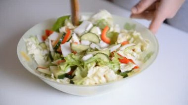 Şef salatayı hazırlar ve malzemeleri karıştırır.