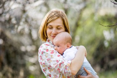 genç kız yemyeşil bir bahçede kollarında küçük bir çocukla ayakta