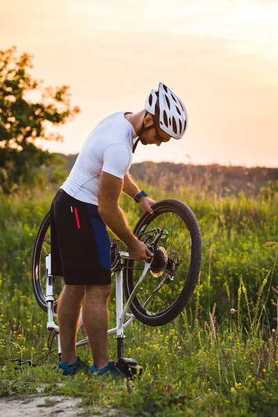 El hombre está reparando su bicicleta rota en el lado de la carretera en el verano . — Foto de Stock