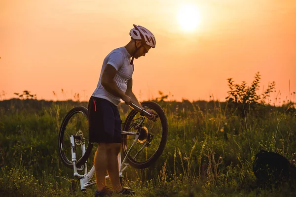 El hombre está reparando su bicicleta rota en el lado de la carretera en el verano . — Foto de Stock