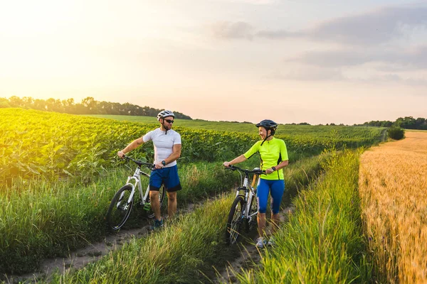 Joven hombre y mujer están conduciendo sus bicicletas en su camino al campo en el verano . — Foto de Stock