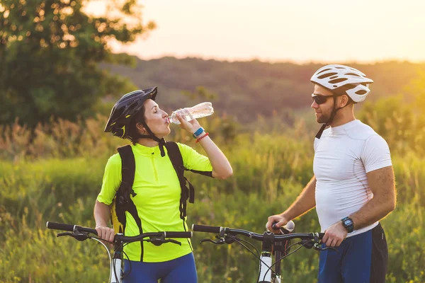 Ciclistas hombre y mujer se detuvieron a beber agua en el viaje . — Foto de Stock