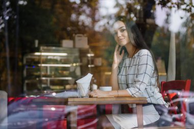 Güzel genç esmer bir kafede oturan ve çay içme.