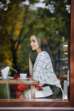 Güzel genç esmer bir kafede oturan ve çay içme.