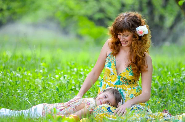 Jonge vrouw met haar dochter ontspannen in het park op het gras in de lente. — Stockfoto