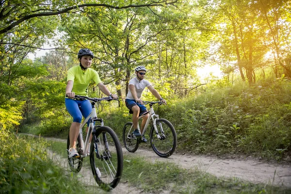Una mujer y un hombre en bicicleta en verano en el parque en bicicletas — Foto de Stock