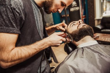Profesyonel kuaför müşteri sakalı kesiyor.