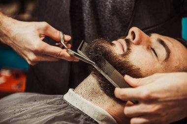 Profesyonel kuaför müşteri sakalı kesiyor.