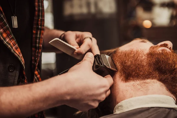 Профессиональный парикмахер стрижет клиентскую бороду. — стоковое фото