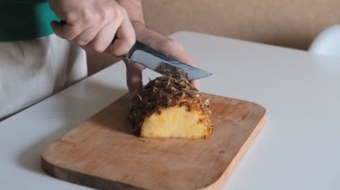 Beyaz bir masada dilimlenmiş ananas ve tahta bir tahta.