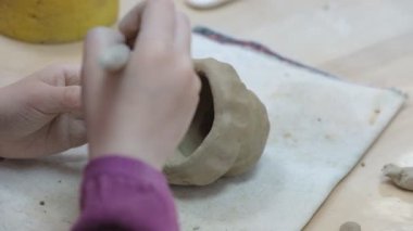 Çocuk seramik atölyede farklı türde kil ürünleri şekillendirmeyi öğreniyor. Çocuk, yaratıcı bir derste kilden bağımsız olarak çalışır..
