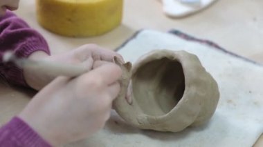 Çocuk seramik atölyede farklı türde kil ürünleri şekillendirmeyi öğreniyor. Çocuk, yaratıcı bir derste kilden bağımsız olarak çalışır..