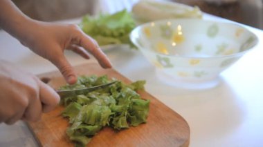 Aşçı tahta üzerinde salata yaprakları keser.
